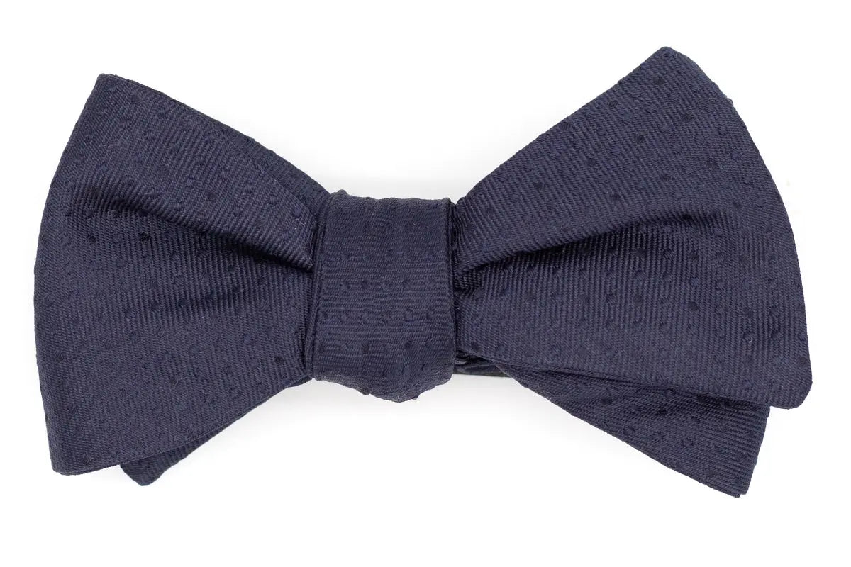 Italian silk mens bow tie. The dark navy color has a textured polka dot design.